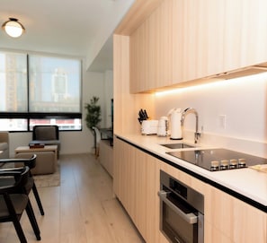 Eine moderne Küche mit Holzschränken, einer schwarzen Arbeitsplatte, einer Edelstahl-Spüle und einem eingebauten Backofen.