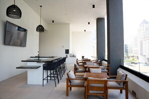 Ein modernes Interieur mit Barbereich, Sitzgelegenheiten und großen Fenstern mit Blick auf die Stadt.