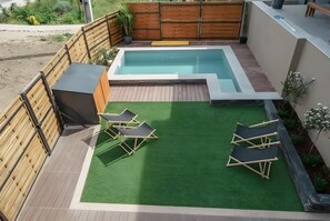 Ein Garten mit Schwimmbad, Kunstrasen und Liegestühlen.