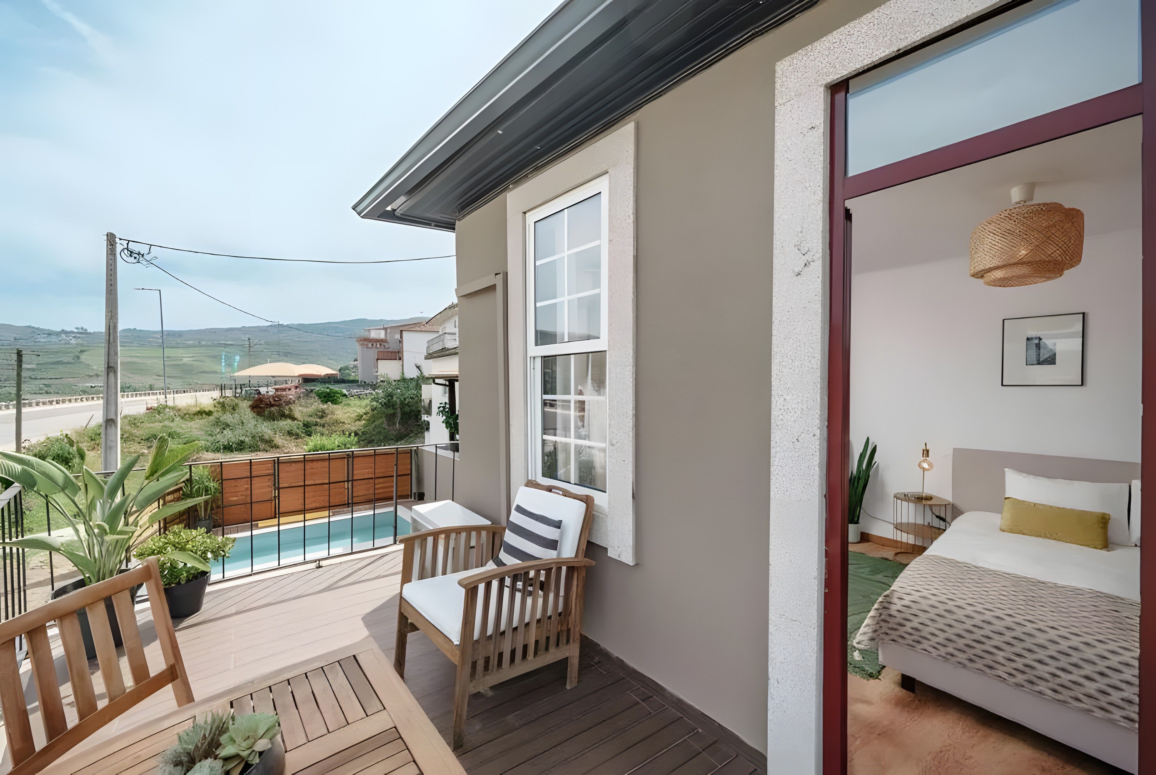 Ein Balkon mit einem Holzstuhl, einem kleinen Pool und Blick auf die umliegende Landschaft.