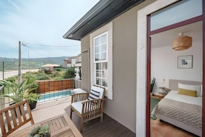 Ein Balkon mit einem Holzstuhl, einem kleinen Pool und Blick auf die umliegende Landschaft.