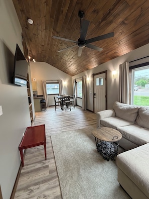 A spacious living area with a ceiling fan, a sofa, a coffee table, and a dining table with chairs. - Bitty Box ~ A charming, comfortable and surprisingly spacious home in Toledo (Toledo)