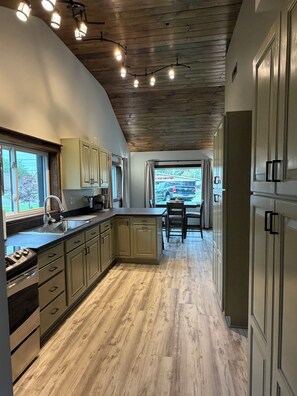 A kitchen with wooden cabinets, a central island, and a view through a window. - Bitty Box ~ A charming, comfortable and surprisingly spacious home in Toledo (Toledo)