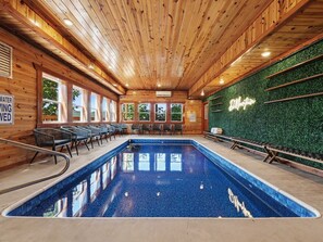 Ein Innenpool mit Holzwänden und -decke, umgeben von Stühlen, mit einer Neonreklame an der Wand.