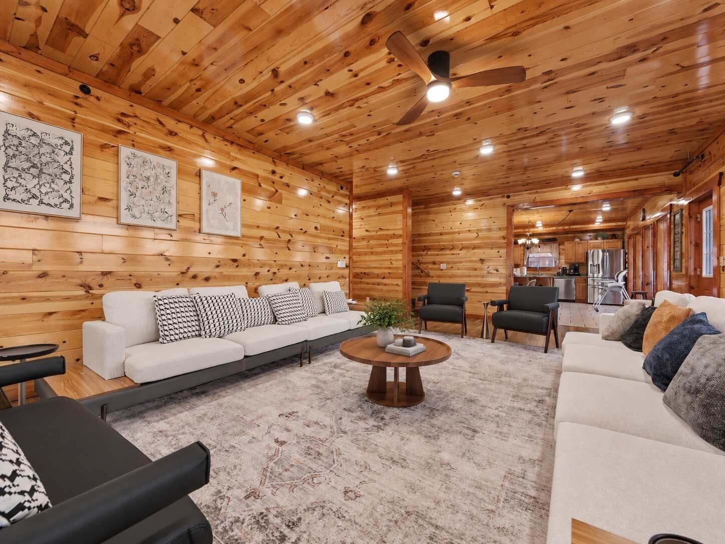 A log cabin interior with a wooden ceiling, a sofa set, a coffee table, and a dining area.