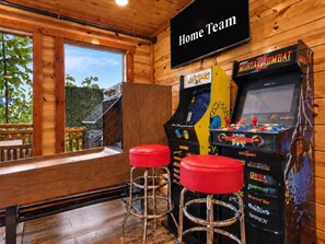 A wooden interior with arcade games, two red stools, and a 'Home Team' sign. - Smoky Mtn Views | Indoor Pool, Hot Tub & Sauna (Sevierville)