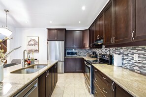 Una cocina moderna con armarios de madera oscura, electrodomésticos de acero inoxidable y un salpicadero de azulejos.