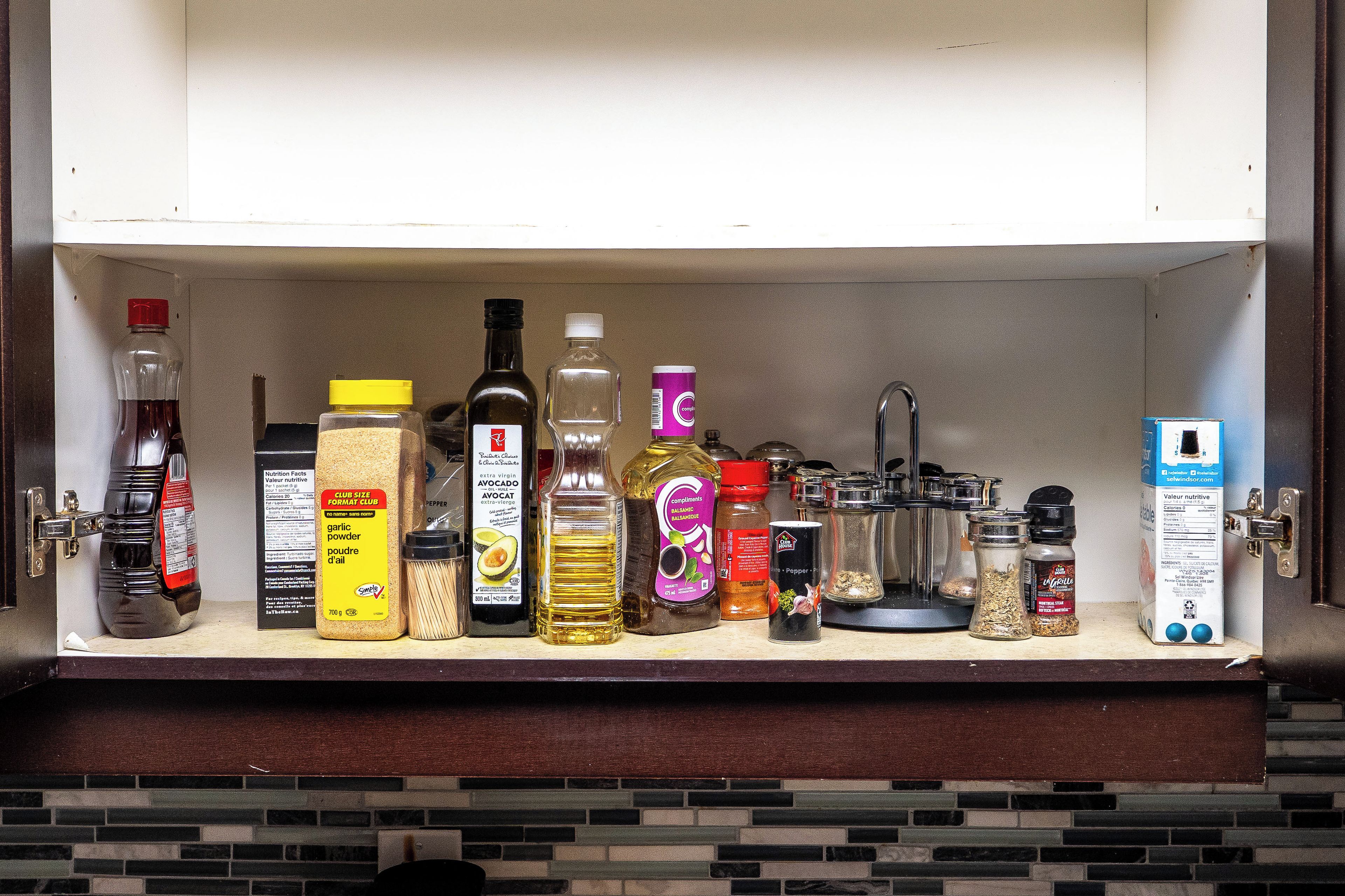 A kitchen shelf stocked with various condiments and spices.