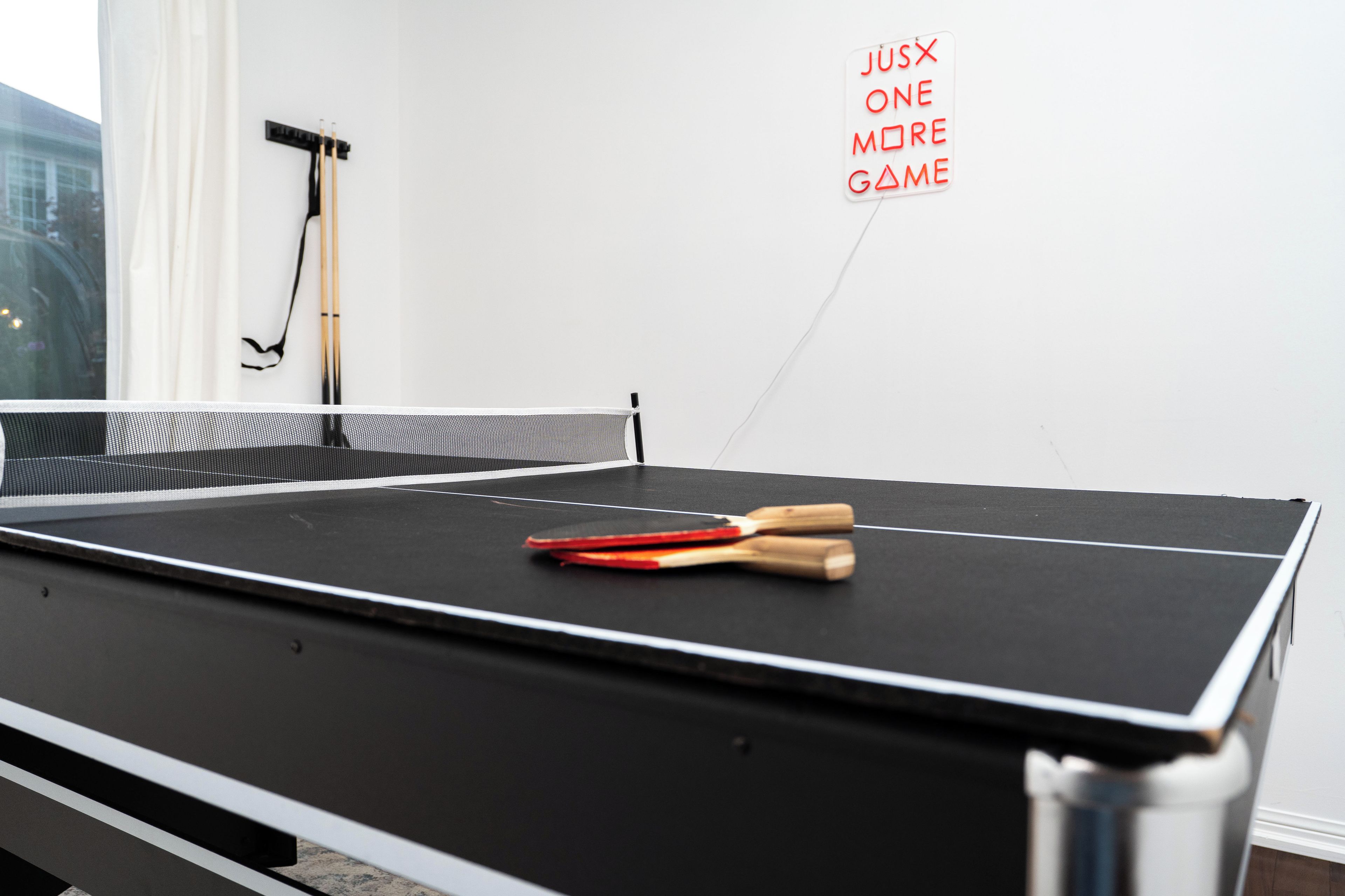 A ping pong table with paddles and a wall-mounted rack.
