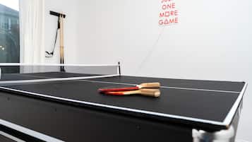A ping pong table with paddles and a wall-mounted rack.