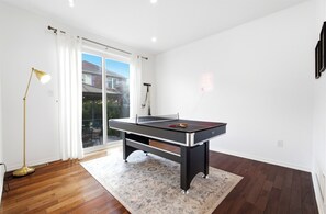 A room with a pool table, a lamp, and a view through a glass door. - Beautiful 4BR Home. Wellness Room, Games, BBQ Yard (Milton)