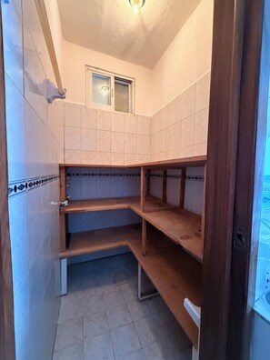 A bathroom with white tiled walls, a window, and wooden shelves. - Ground-floor apartment at "Sun House" (Puerto Vallarta)
