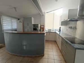 A kitchen with a curved countertop, a microwave, a coffee maker, and cabinets. - Maison de Campagne 9 places (Lançon-Provence)