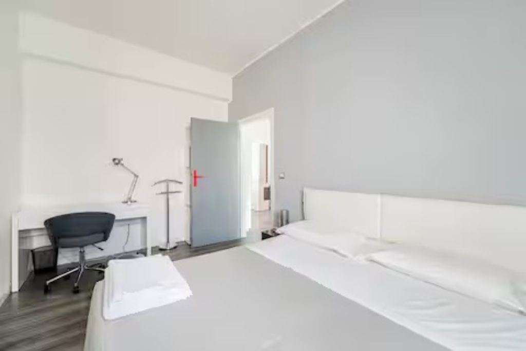 A hotel room with a bed, a desk, and a chair.