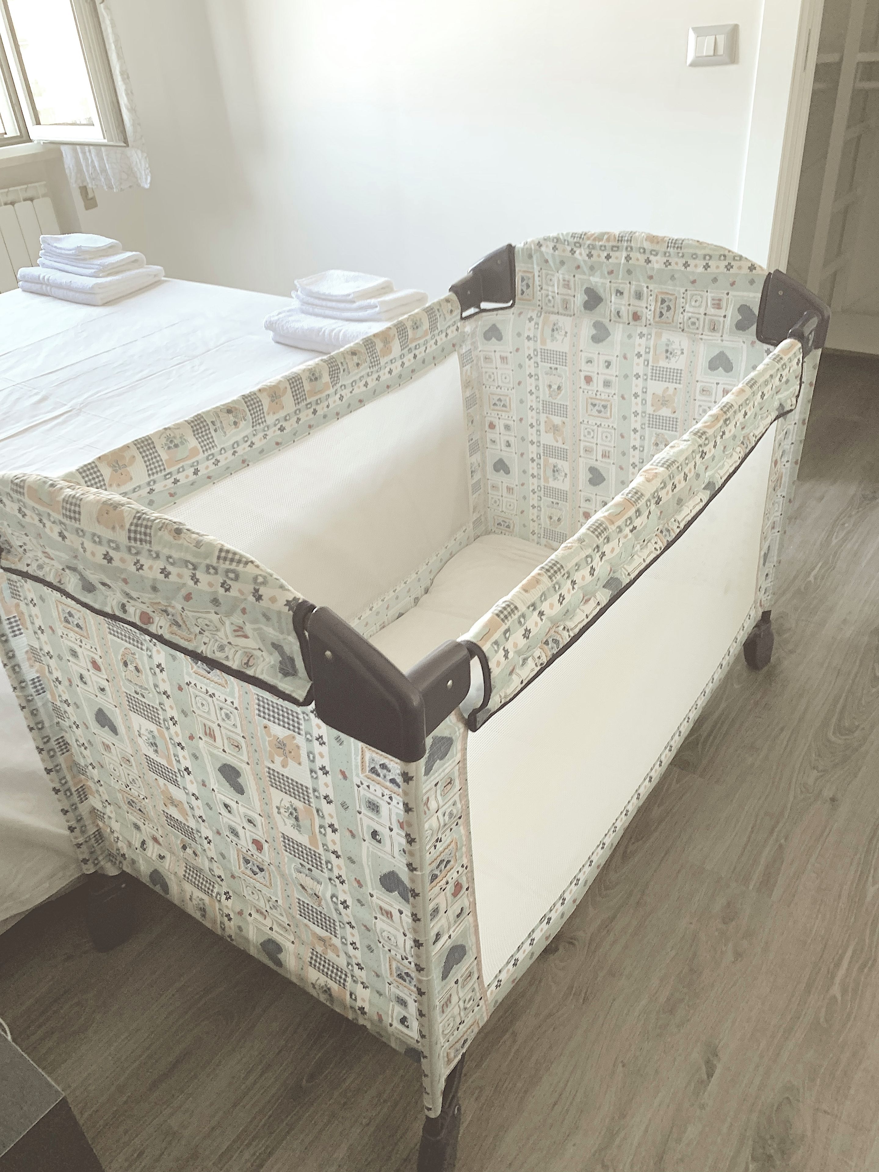 Eine Babybadewanne mit einem gemusterten Design steht in einem Raum mit Holzboden und einer weißen Heizung.