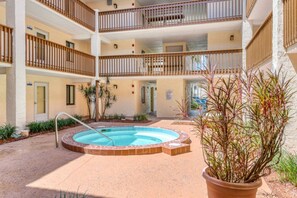Ein mehrstöckiges Gebäude mit einem zentralen Innenhof, der einen Swimmingpool, Blumentöpfe und eine Ziegelumrandung umfasst.