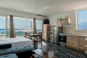 Ett modernt hotellrum med balkong, ett litet kök, en säng och en sittgrupp.