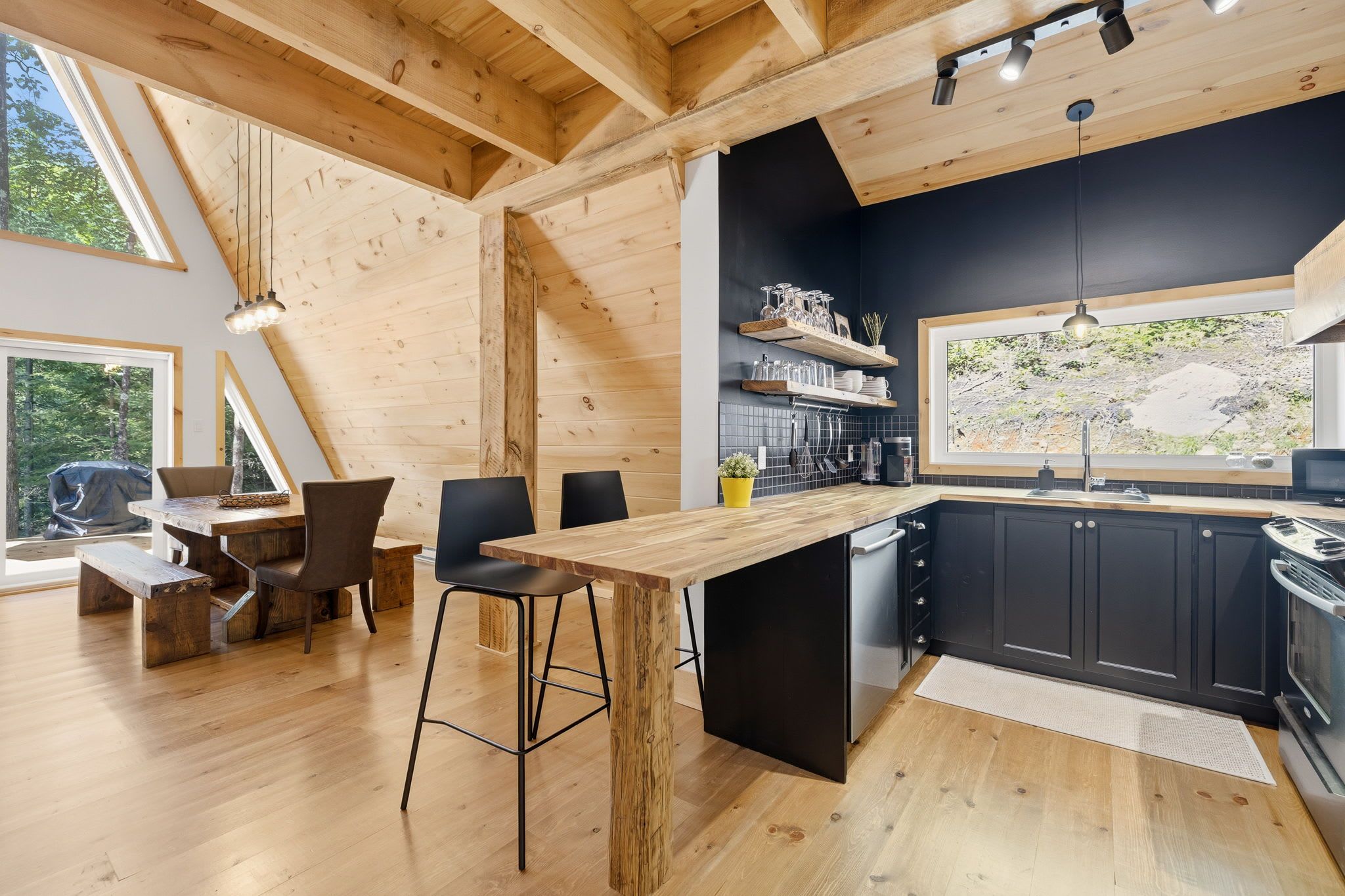 A modern kitchen with wooden beams, a bar area, and a dining space with a view.