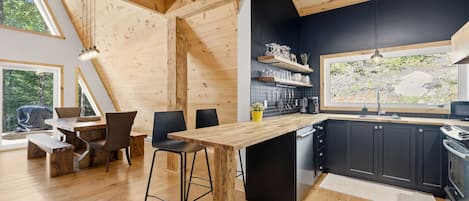 A modern kitchen with wooden beams, a bar area, and a dining space with a view.