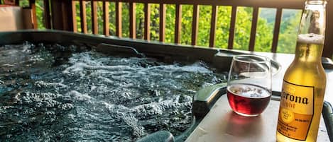 A hot tub with a glass of red wine and a Corona Light beer bottle.