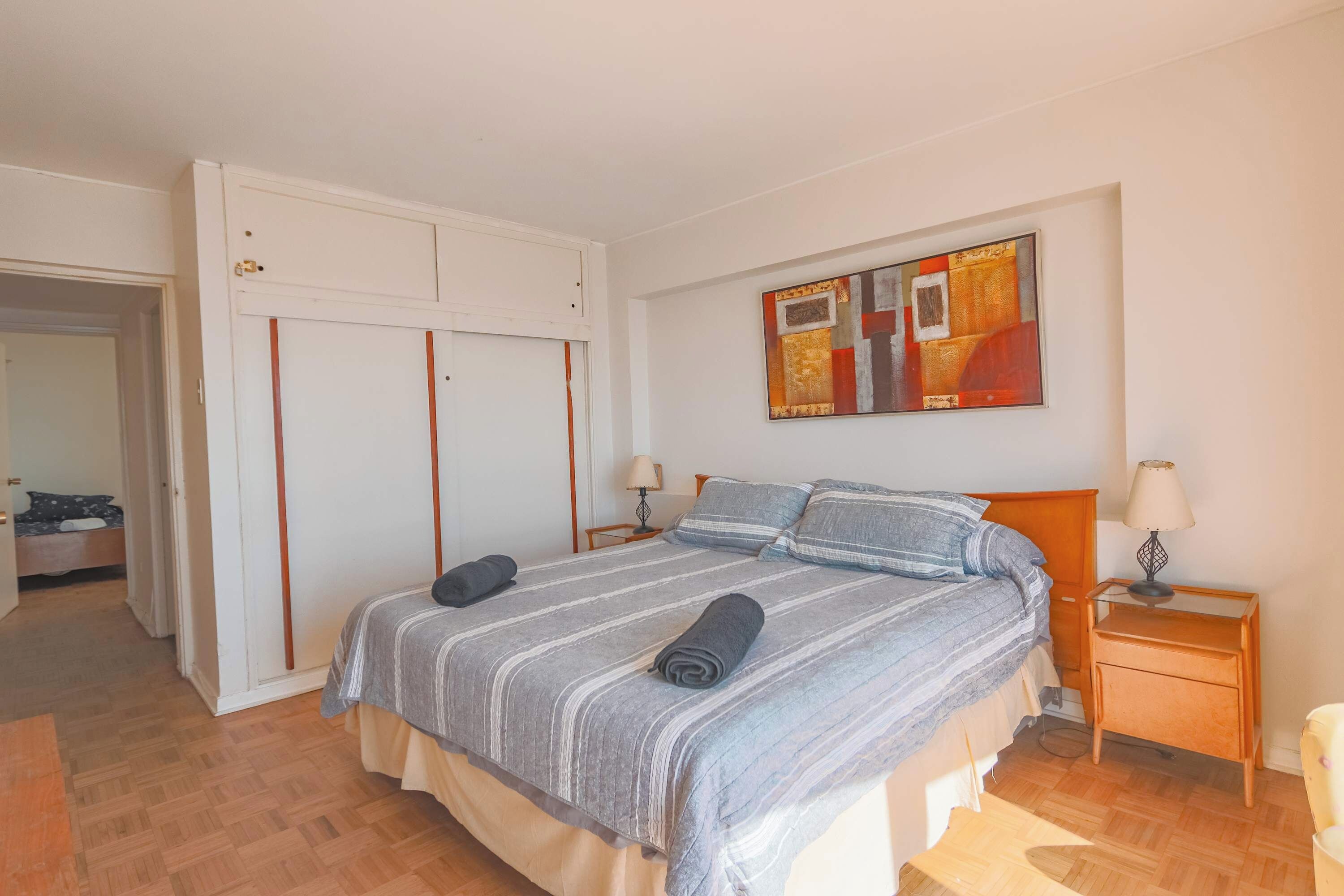 Ein Schlafzimmer mit einem Bett, Nachttischen, einem Kleiderschrank und einem Bild an der Wand.