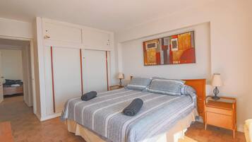 Ein Schlafzimmer mit einem Bett, Nachttischen, einem Kleiderschrank und einem Bild an der Wand.