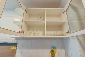 Een keuken met witte kastjes, een spoelbak en een betegelde achterwand.