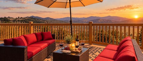 A balcony with wicker furniture, a table with a bottle of wine, and a candle.