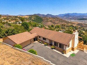 Ein zweistöckiges Haus mit Garage, eingebettet in eine hügelige Landschaft.