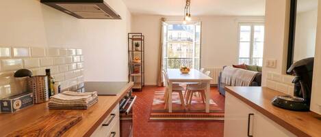 A modern kitchen with a wooden countertop, a built-in stove, and a dining area with a table and chairs.
