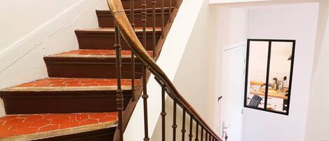 Een wenteltrap met houten treden en een zwarte metalen balustrade, leidend naar een deur met een raam.