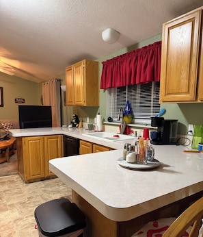 A kitchen with wooden cabinets, a white countertop, a red window valance, and a built-in dishwasher. - Beautiful Mountain Views! 3 Bed / 2 Bath house overlooking Pebble Creek Ski Hill (Inkom)