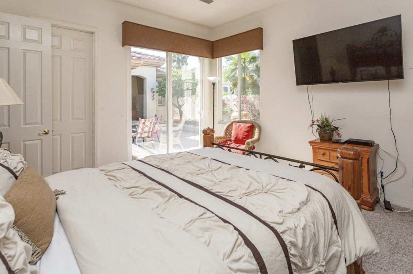 Une chambre à coucher avec un lit, une télévision, une chaise et une vue sur l’extérieur.