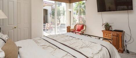 Une chambre à coucher avec un lit, une télévision, une chaise et une vue sur l’extérieur.