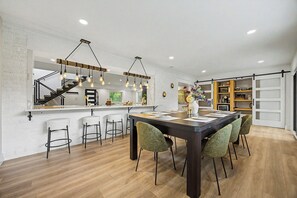 A modern kitchen with a central island, bar stools, and a staircase leading to an upper level. - Lockwood Luxe - Arcade, Axe Throwing, Firepit, Two Kings (Atlanta)