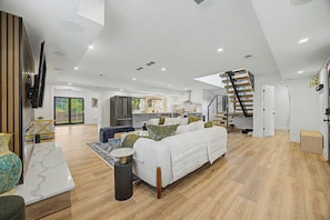 A spacious living area with a large sofa, a coffee table, and a TV mounted on the wall. - Lockwood Luxe - Arcade, Axe Throwing, Firepit, Two Kings (Atlanta)