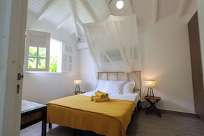 Ein Schlafzimmer mit Bett, Nachttischlampen, einem Fenster und einem Deckenventilator.