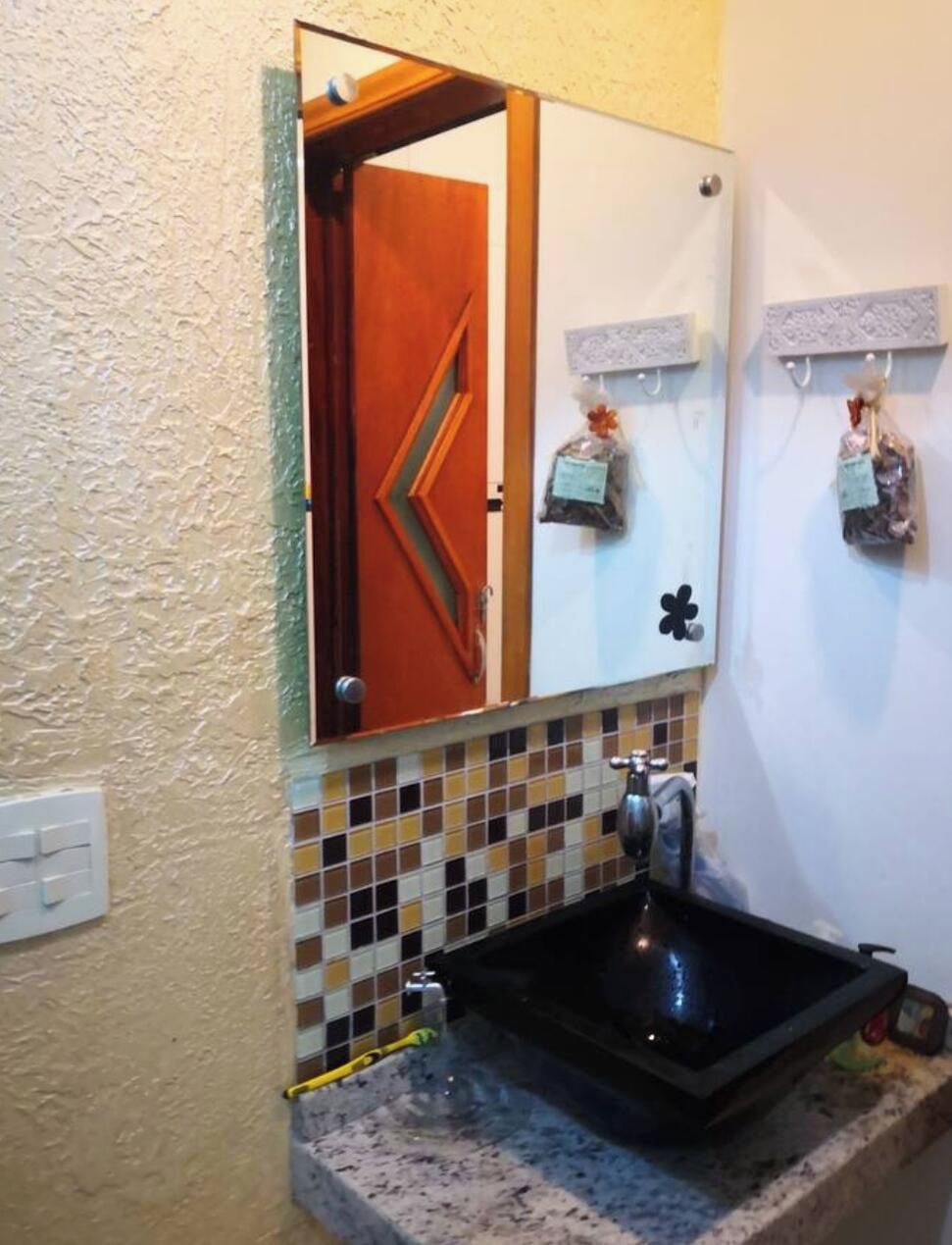Casa de banho com lavatório, espelho e porta para outro espaço.