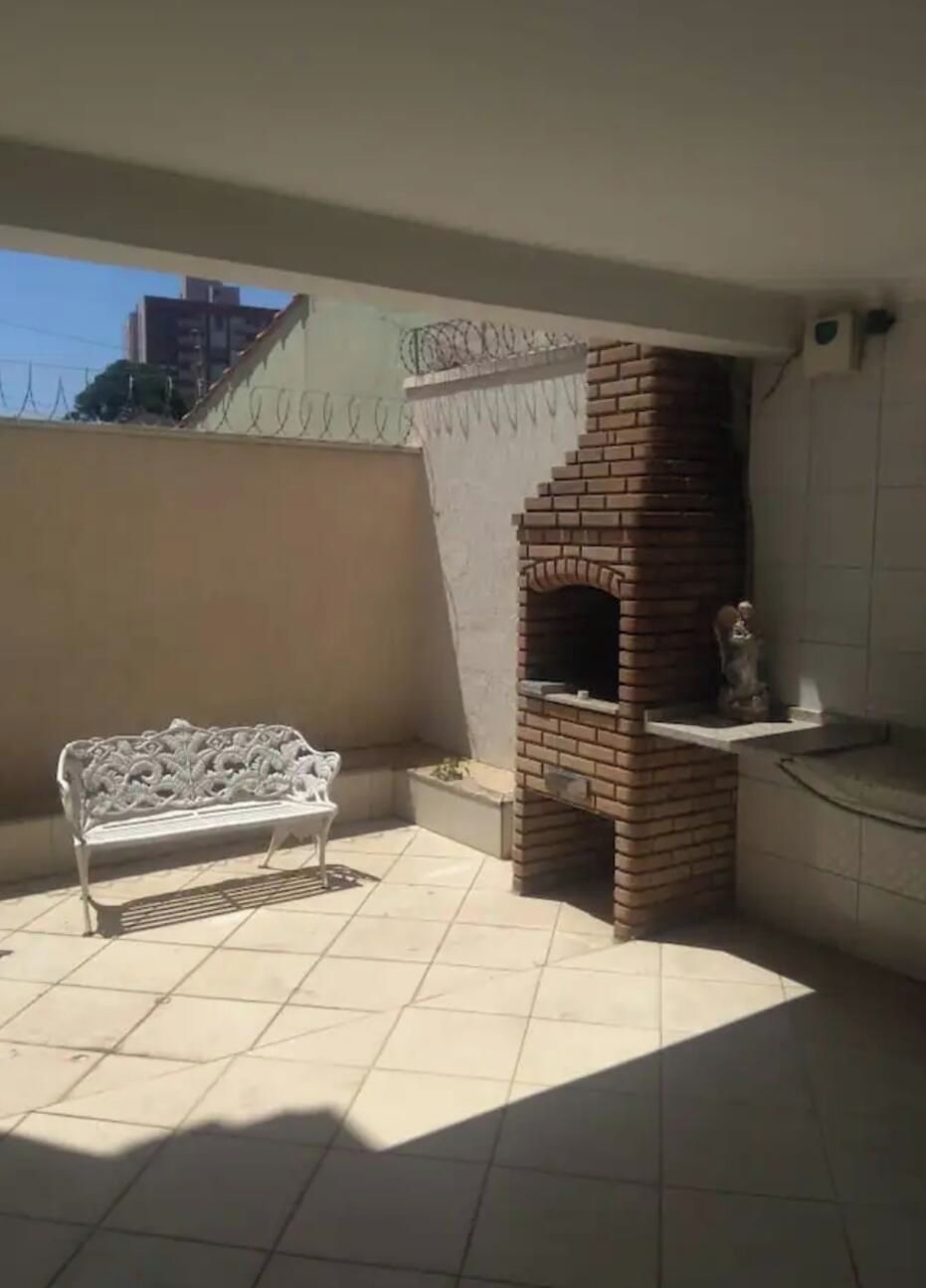 Um pátio com forno de tijolos, um banco branco e piso de azulejos.
