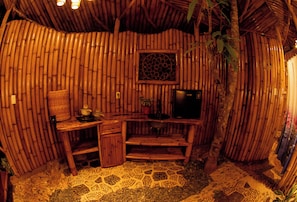 A bamboo room with a desk, chair, and a television.