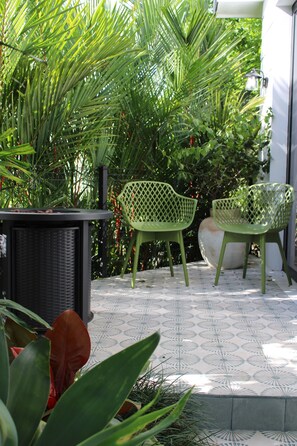Eine Terrasse mit Tisch, zwei Stühlen und einem Blumentopf.