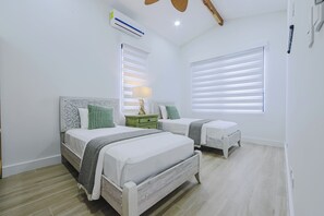 Ein Schlafzimmer mit zwei Betten, einem Nachttisch, einer Lampe und einem Deckenventilator.