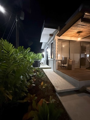 A modern house with a covered outdoor seating area and a glass door leading to a room with a desk and chair. - Casa Volcancito- Volcan View (Provincia de Alajuela)