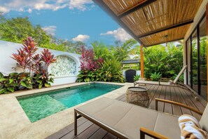 A poolside area with a lounge chair, a wicker table, and lush tropical plants. - Casa Volcancito- Volcan View (Provincia de Alajuela)