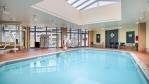 Ein Hotelpoolbereich mit freiem Blick auf den Pool, Liegestühlen und einem Glasdach.
