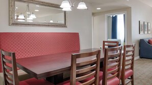Ein Essbereich mit Holztisch und Stühlen, einer rot gepolsterten Bank und einem großen Spiegel über dem Tisch.