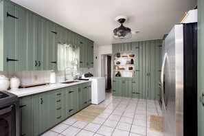 A kitchen with green cabinets, a white countertop, a built-in oven, and a stainless steel refrigerator. - Choosing Texas (Amarillo)