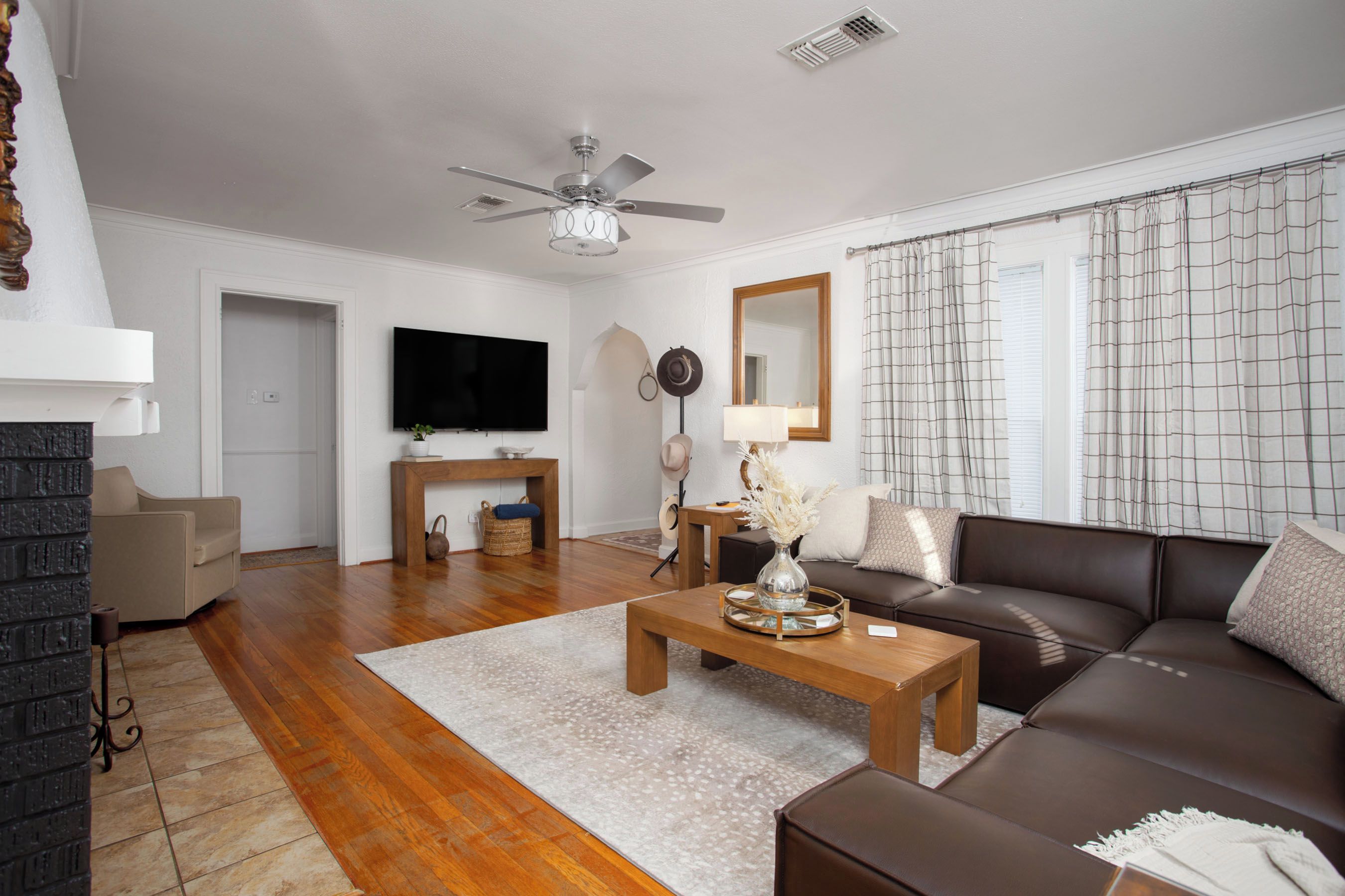A modern living room with a brown leather sofa, wooden coffee table, and a flat-screen TV mounted on the wall.