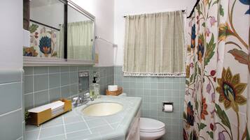 Un baño con lavamanos, inodoro y cortina de ducha.