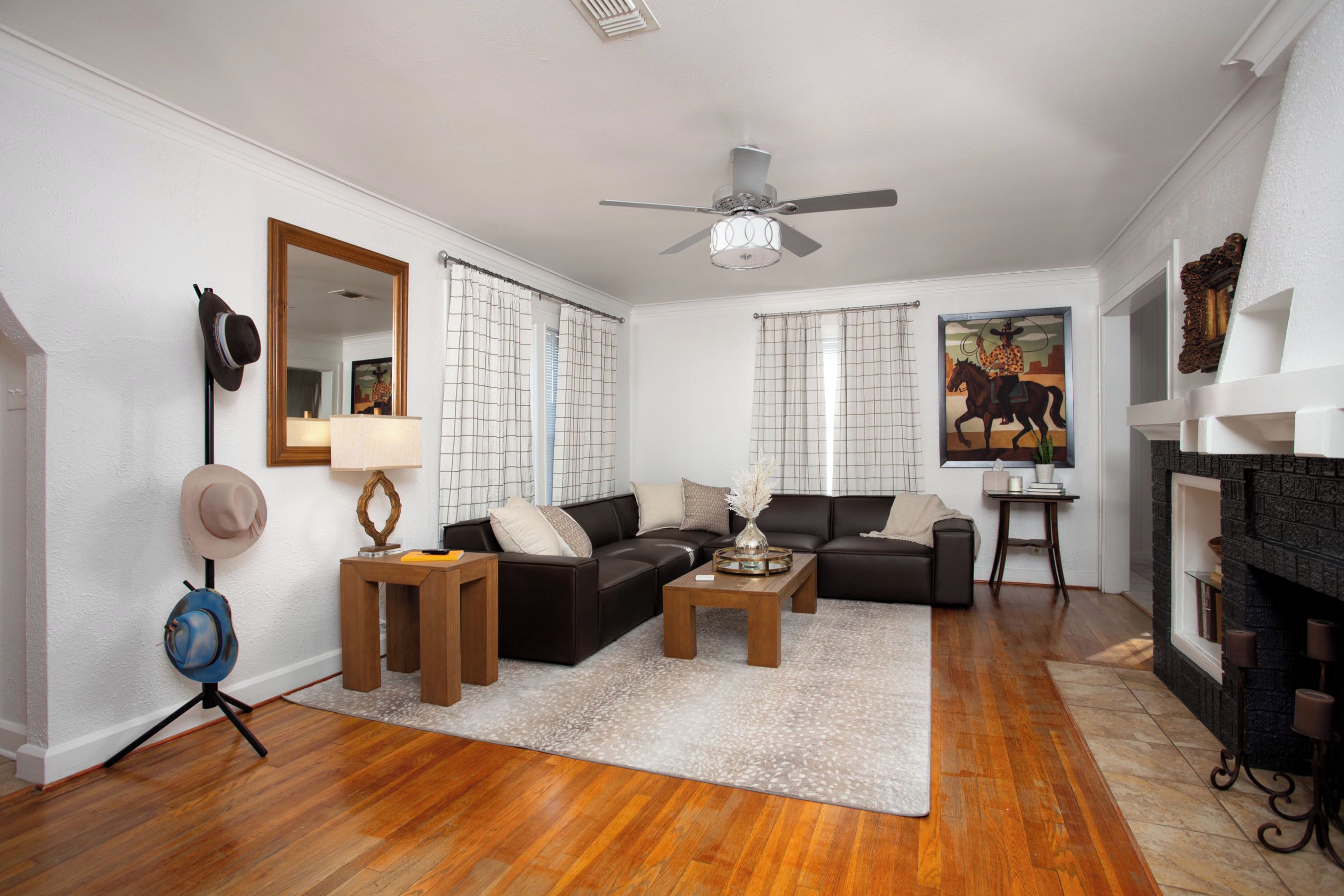 A living room with a fireplace, a ceiling fan, and a large mirror.